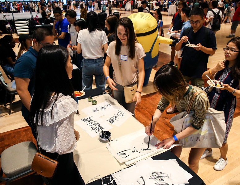 Students use paint to practice writing characters at an event