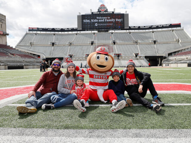 A family sits with Brutus midfield at Ohio Stadium during Sibs, Kids and Family Day 2023