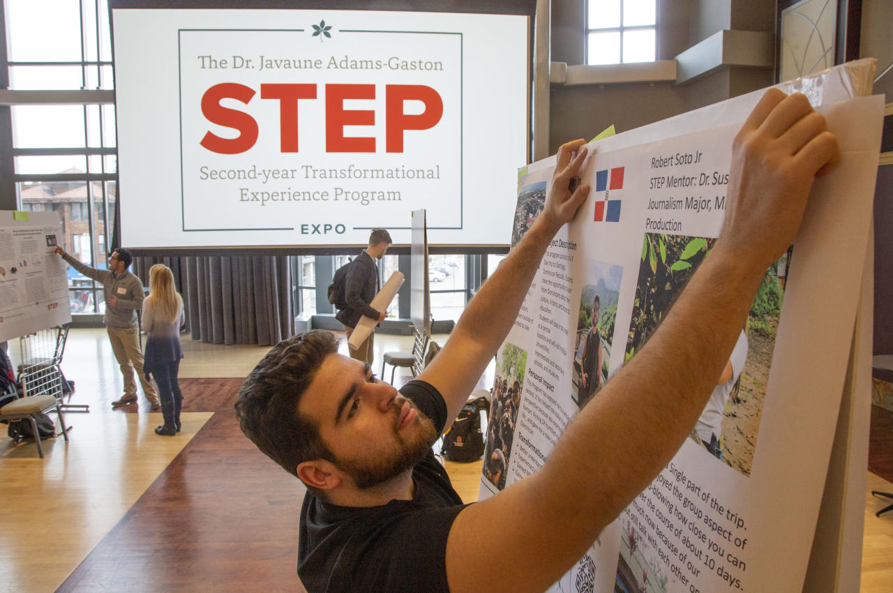 A student makes final adjustments to their project display prior to the STEP Expo