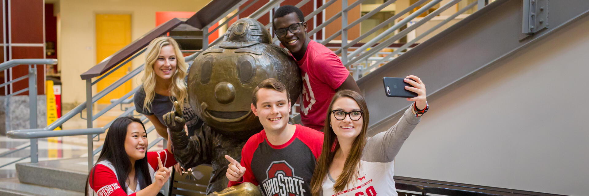 Five people pose for a selfie with Bronze Brutus in the Ohio Union
